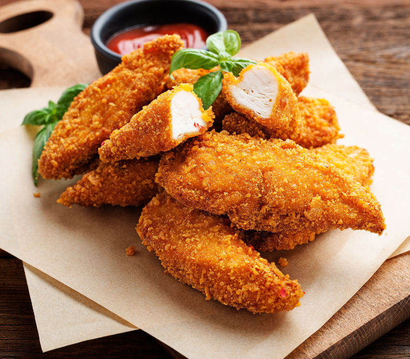 Delicious crispy fried breaded chicken breast strips with ketchup
